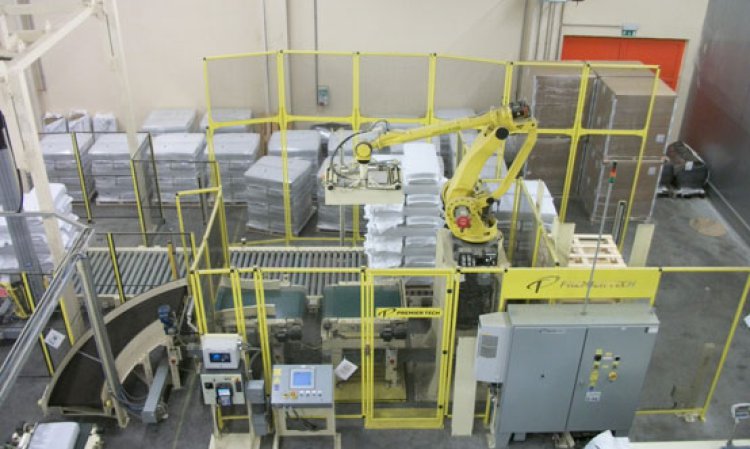 A bale (lower left) is conveyed toward the model AR-200 series robotic palletising station, the robot of which can be fitted with a variety of different gripping mechanisms.